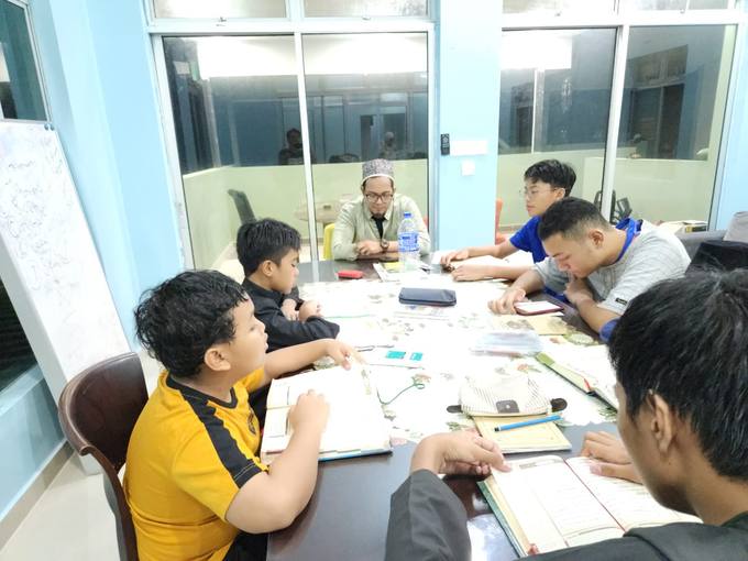Pelajar dan guru duduk mengelilingi meja semasa sesi belajar