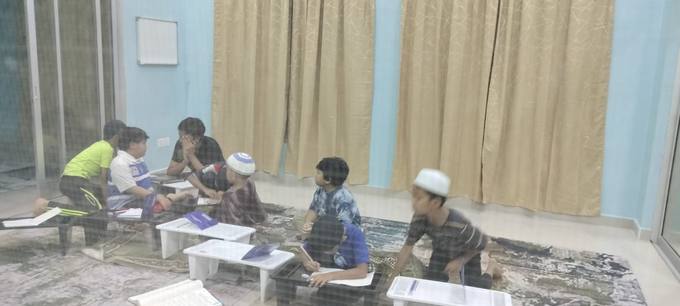 Pelajar membaca Al-Quran di meja rendah