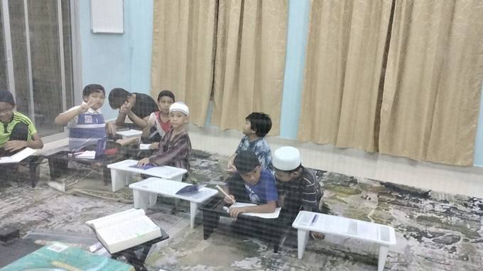 Pelajar menulis di meja rendah di dalam kelas