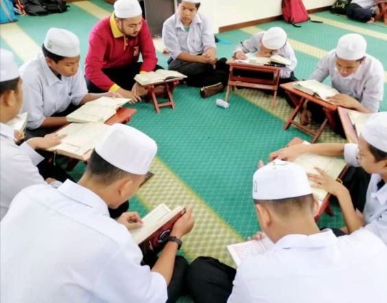 Kelas mengaji berkumpulan bersama guru di dalam dewan